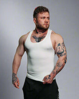 Man wearing a white tank top with tattoos on a gray background